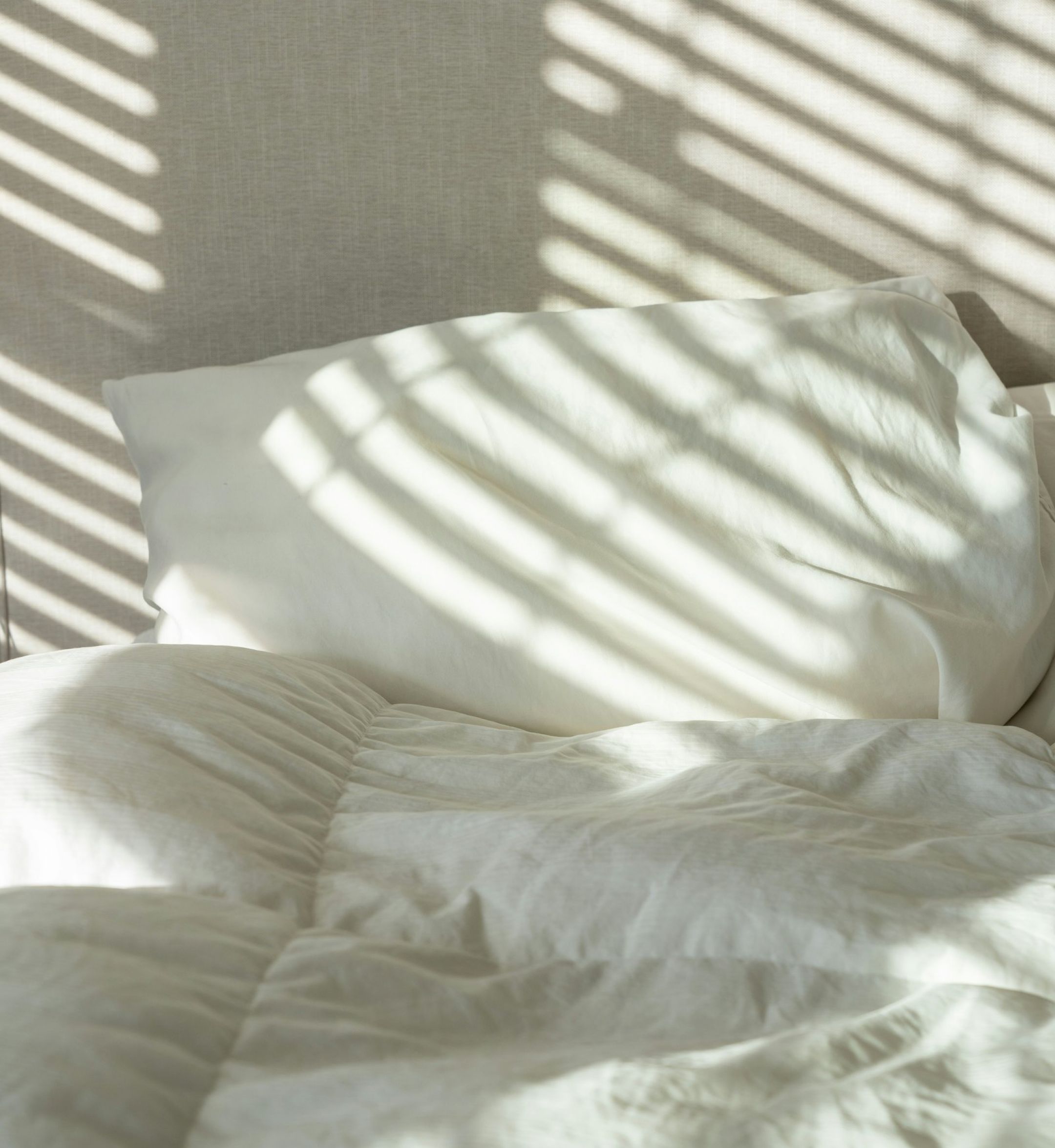 The Sloan at LoSo apartments in Charlotte, NC - unmade bed with sunlight streaming in the window through the blinds