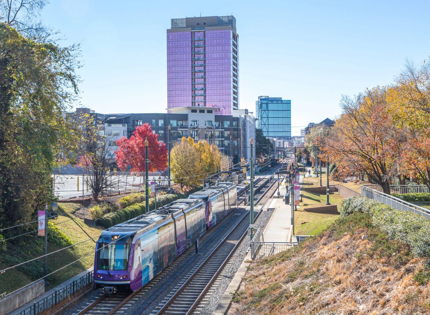 The Sloan at LoSo Apartments in Charlotte, NC, neighborhood area public transportation train with the city skyline in the background